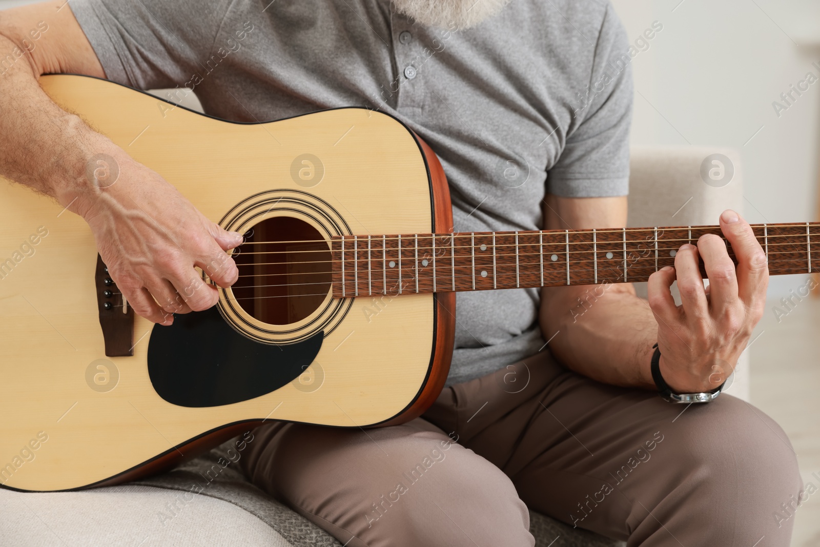 Photo of Relaxing hobby. Senior man playing guitar on sofa at home, closeup