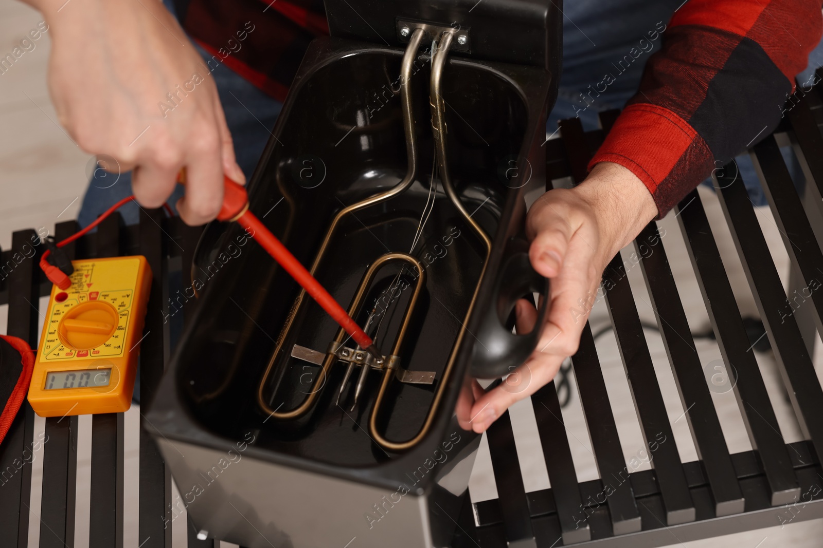 Photo of Relaxing hobby. Man testing deep fryer with multimeter indoors, closeup