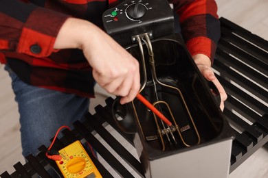 Photo of Relaxing hobby. Man testing deep fryer with multimeter indoors, closeup