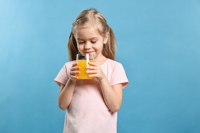 Photo of Girl with glass of orange juice on light blue background. Refreshing drink