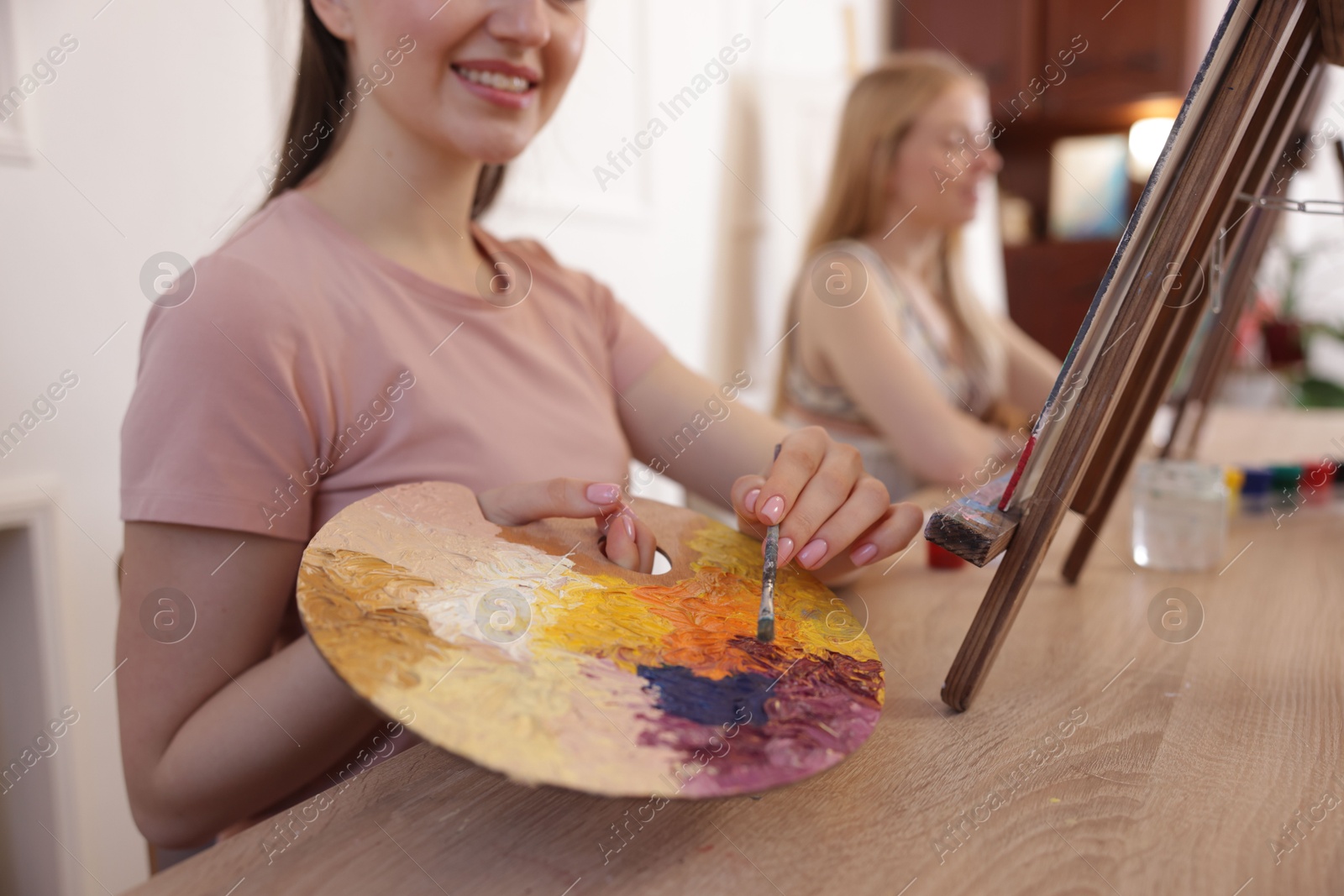 Photo of Smiling woman with palette and brush learning to draw at table in class, closeup