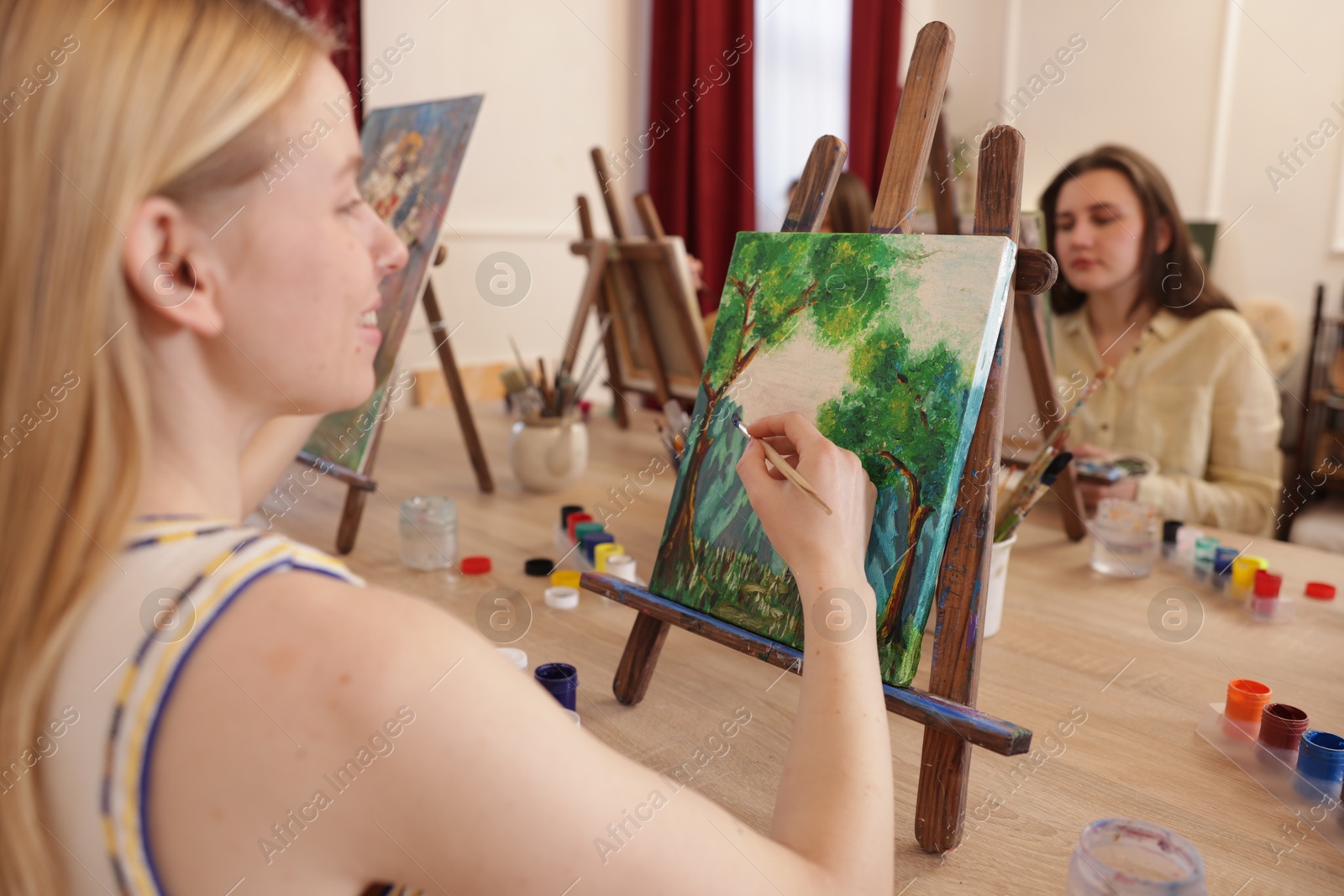 Photo of Smiling woman with brush learning to draw at table in class