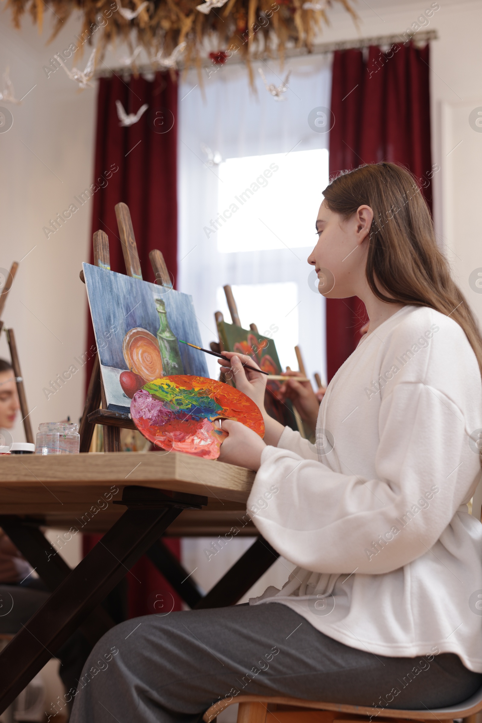 Photo of Woman with palette and brush learning to draw at table in class