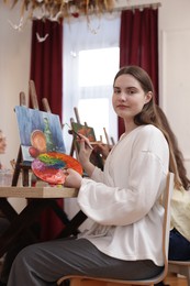 Photo of Woman with palette and brush learning to draw at table in class