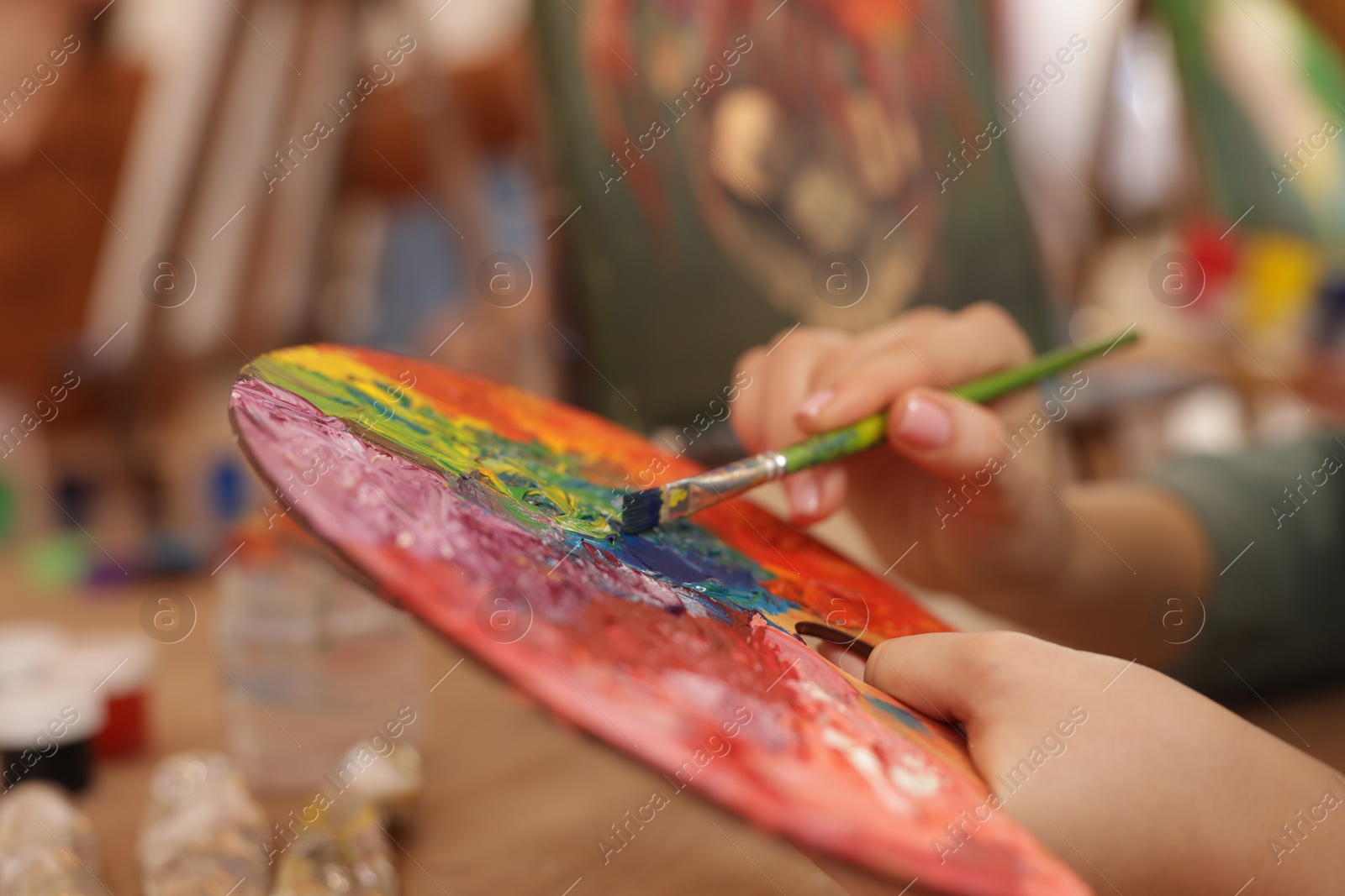 Photo of Woman with palette and brush learning to draw at table in class, closeup