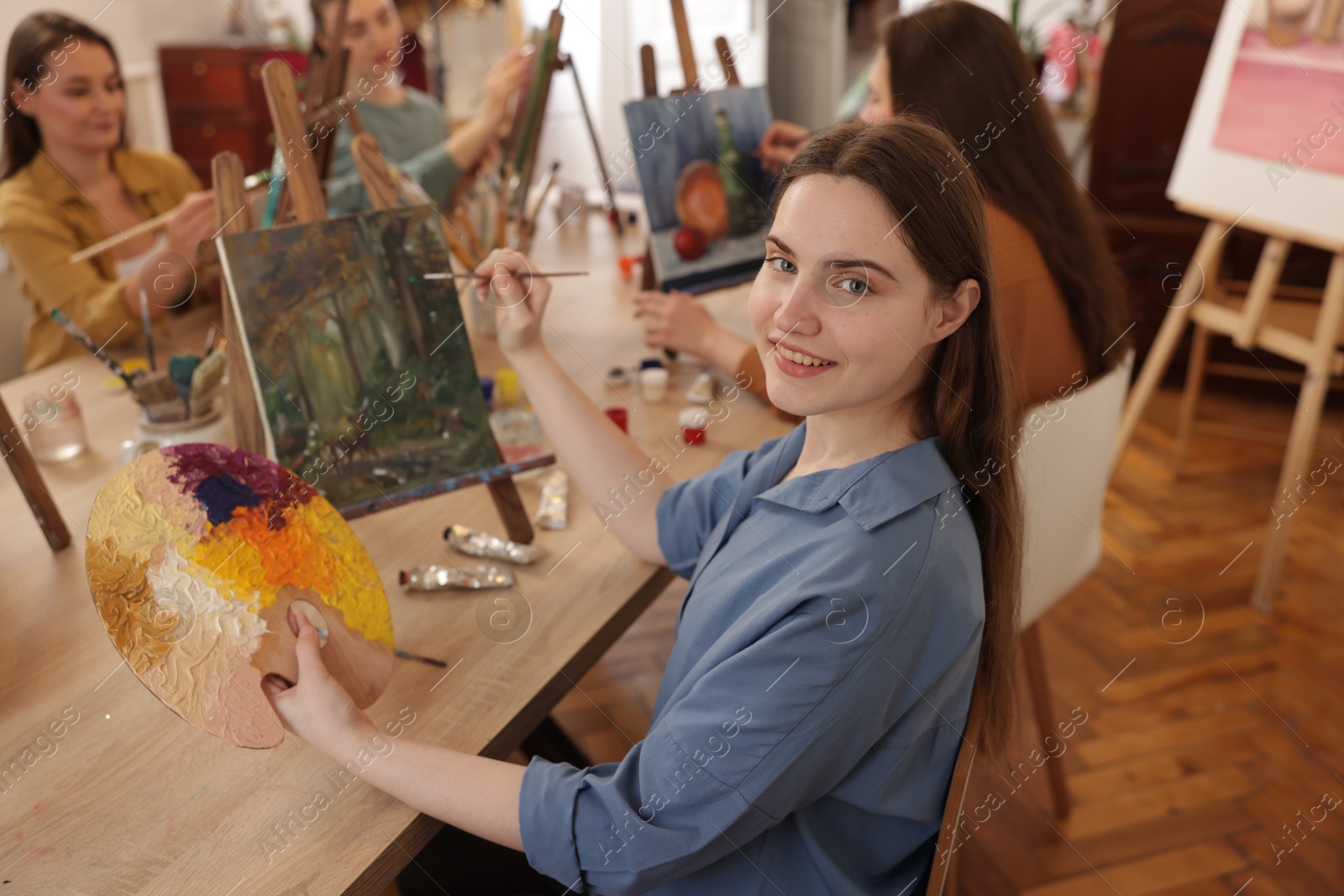 Photo of Group of women learning to draw at wooden table in class