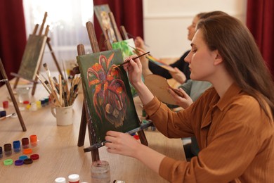 Photo of Group of women learning to draw at wooden table in class