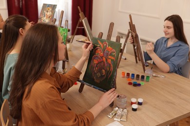 Photo of Group of women learning to draw at wooden table in class