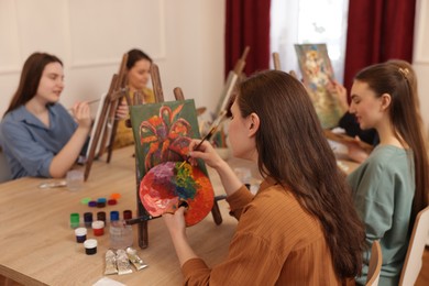 Photo of Group of women learning to draw at wooden table in class