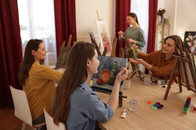 Photo of Group of women learning to draw at wooden table in class