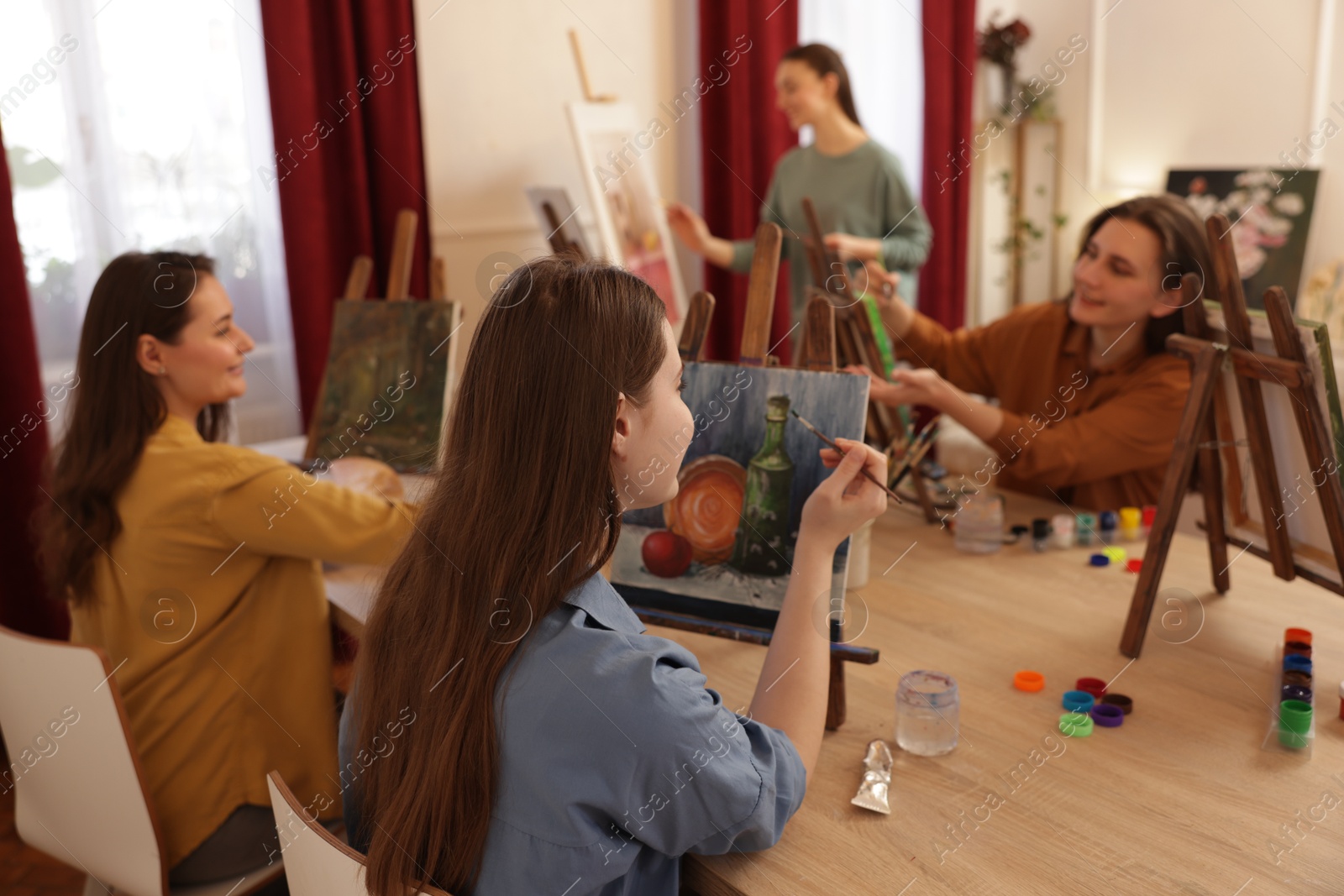 Photo of Group of women learning to draw at wooden table in class