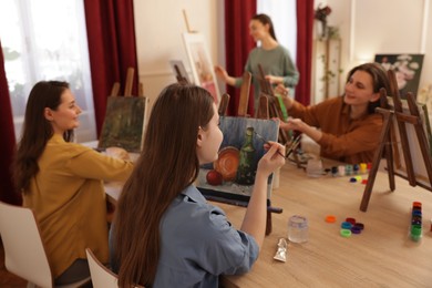 Group of women learning to draw at wooden table in class