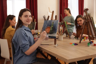 Photo of Group of women learning to draw at wooden table in class