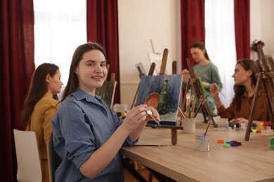 Photo of Group of women learning to draw at wooden table in class