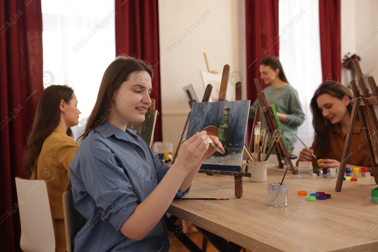 Photo of Group of women learning to draw at wooden table in class