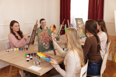 Photo of Group of women learning to draw at wooden table in class