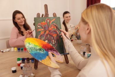 Group of women learning to draw at wooden table in class, focus on picture