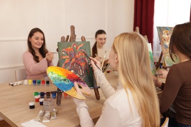 Photo of Group of women learning to draw at wooden table in class