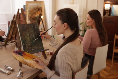 Photo of Group of women learning to draw at wooden table in class