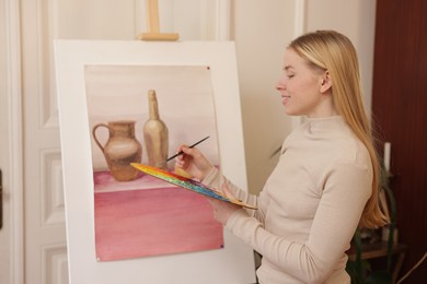 Photo of Smiling woman with palette and brush learning to draw in class