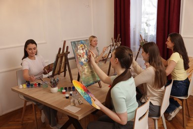 Group of women learning to draw at wooden table in class