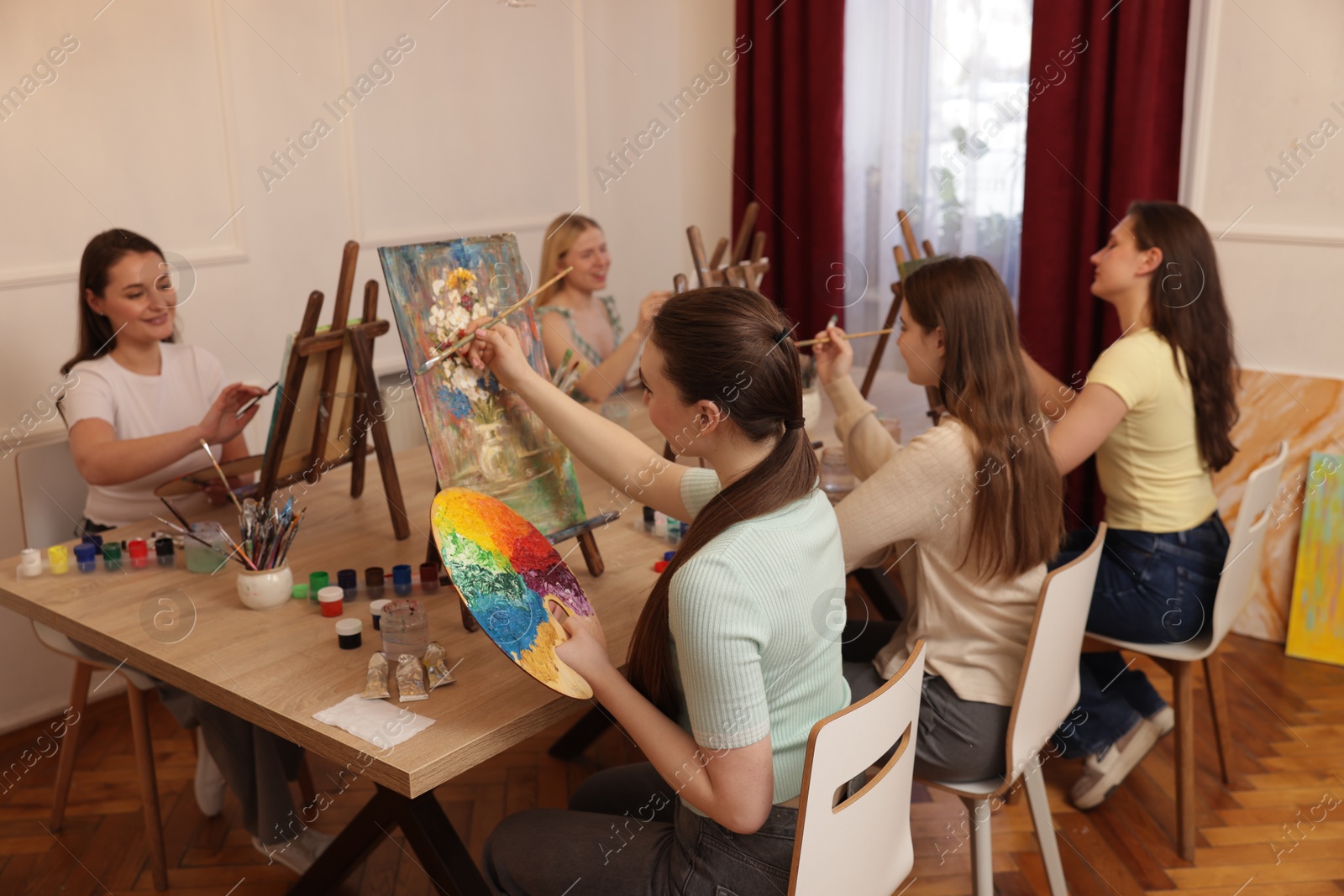 Photo of Group of women learning to draw at wooden table in class