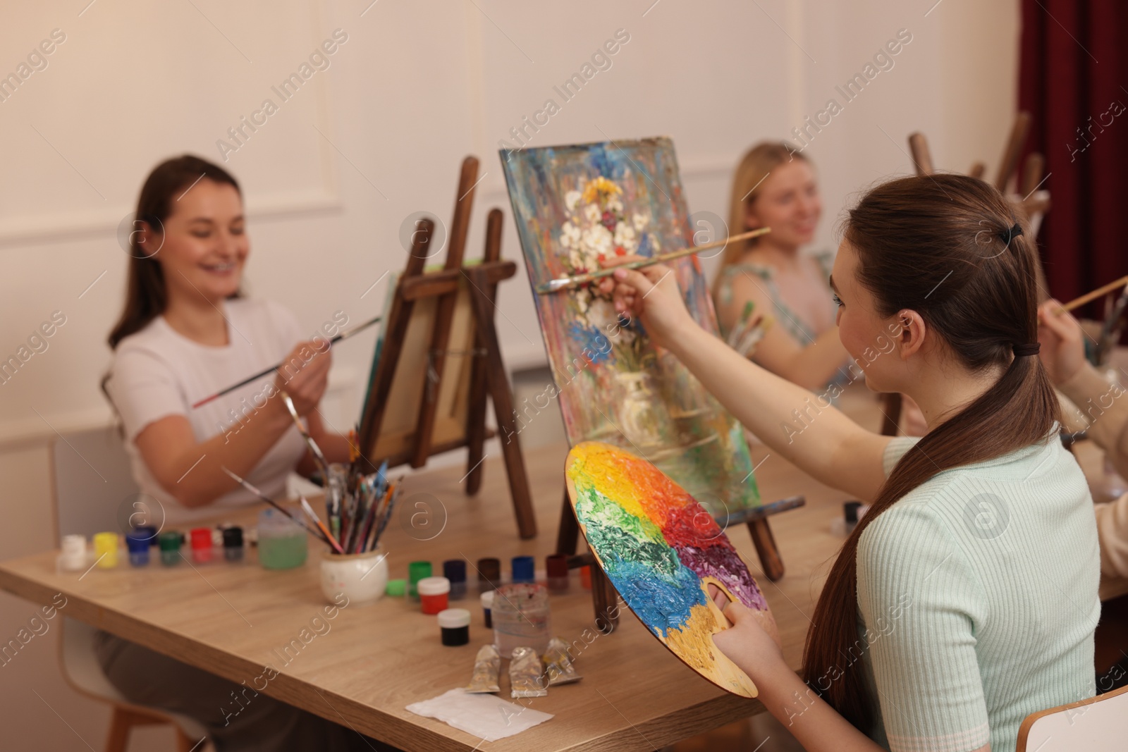 Photo of Group of women learning to draw at wooden table in class