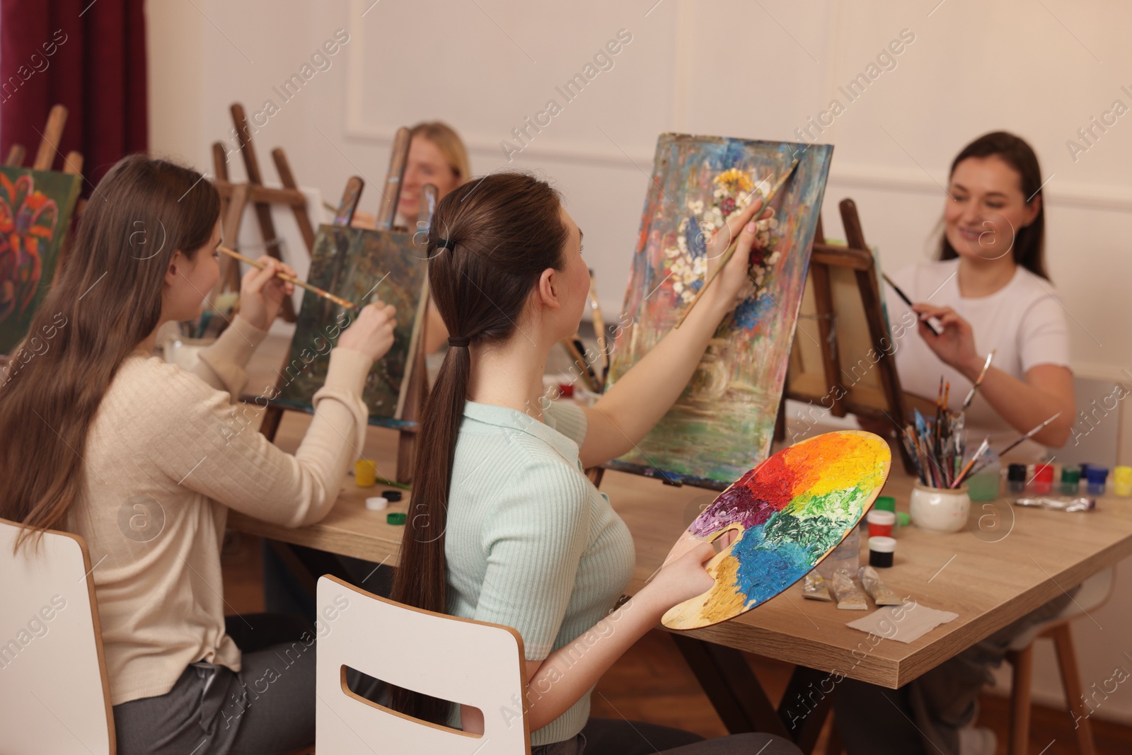 Photo of Group of women learning to draw at wooden table in class