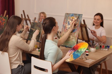 Photo of Group of women learning to draw at wooden table in class