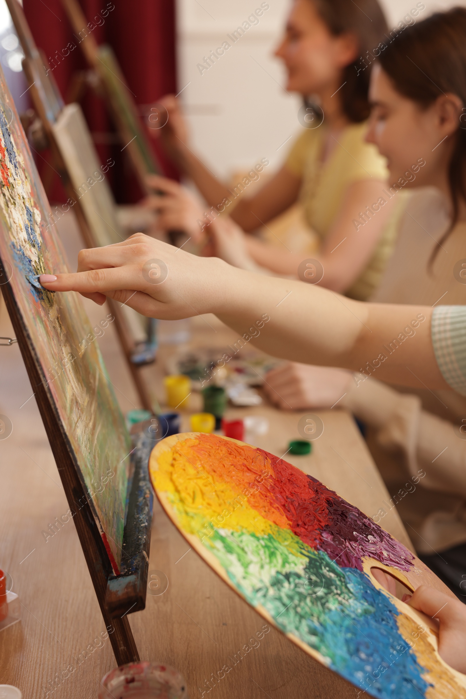 Photo of Group of women learning to draw at wooden table in class, closeup