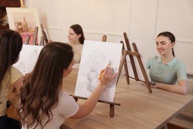 Photo of Group of women learning to draw at wooden table in class