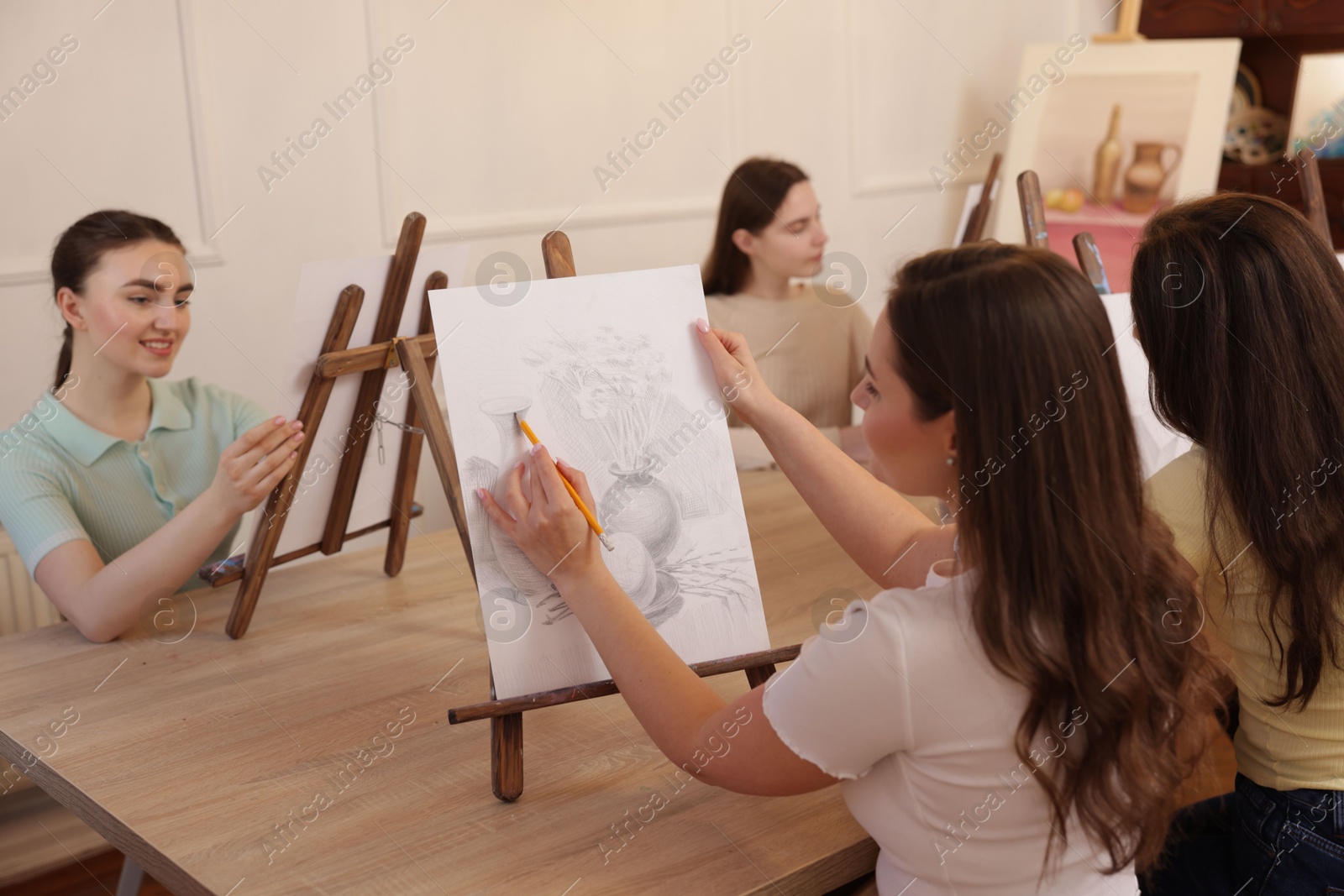 Photo of Group of women learning to draw at wooden table in class