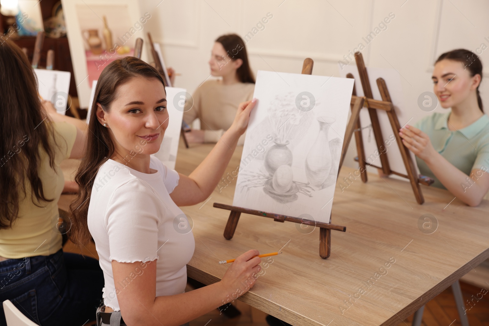 Photo of Group of women learning to draw at wooden table in class