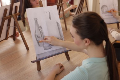 Photo of Group of women learning to draw at wooden table in class