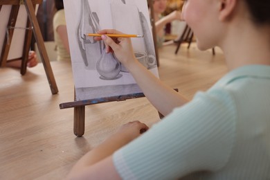 Photo of Woman with pencil learning to draw at wooden table in class, closeup