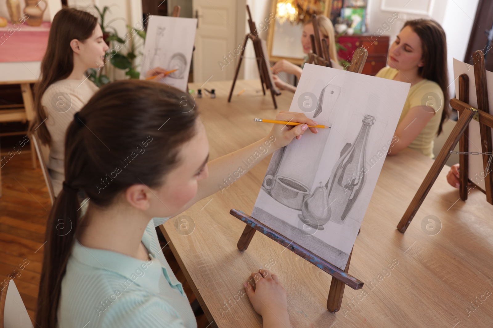 Photo of Group of women learning to draw at wooden table in class