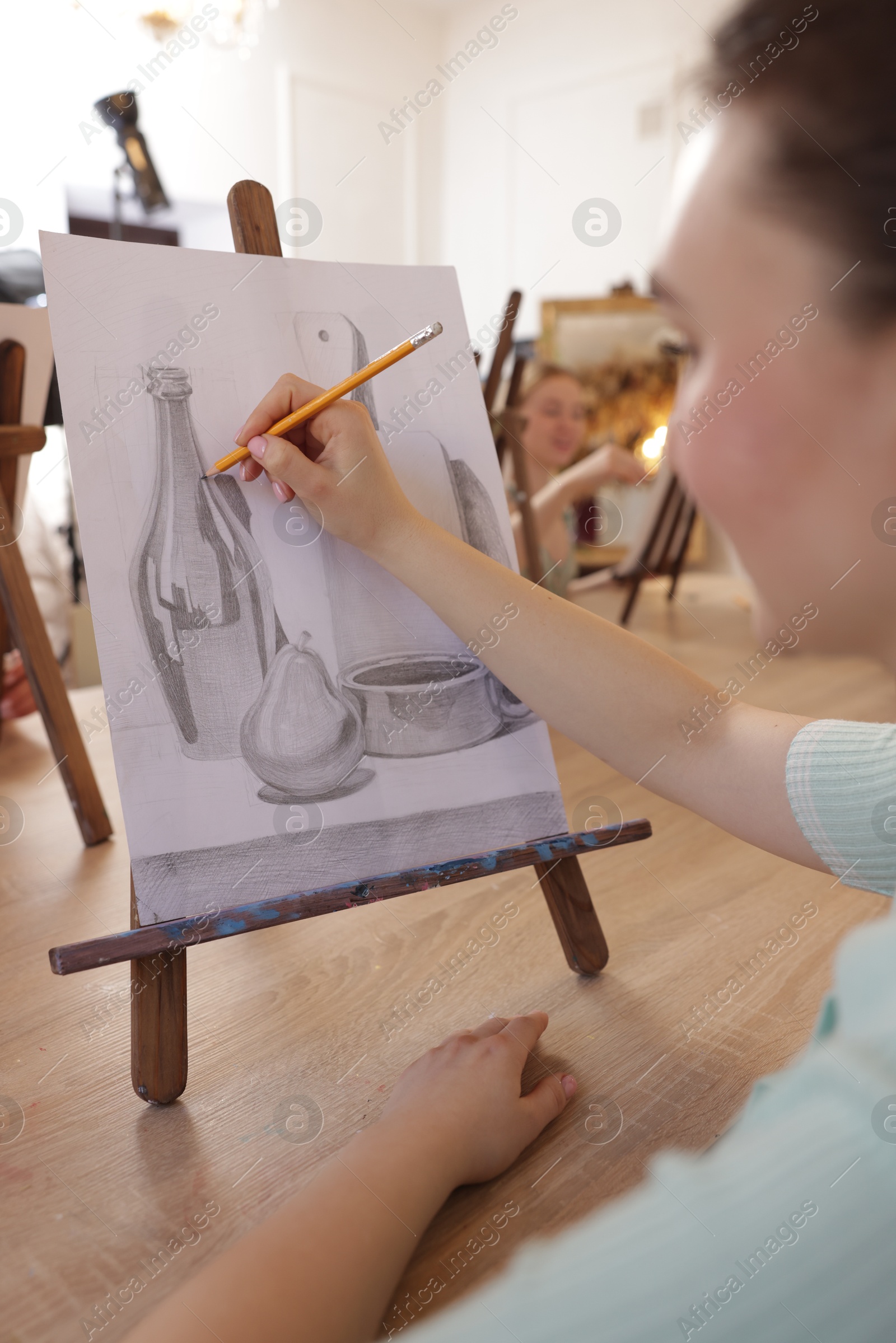 Photo of Woman with pencil learning to draw at wooden table in class, closeup