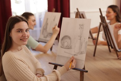 Photo of Group of women learning to draw at wooden table in class