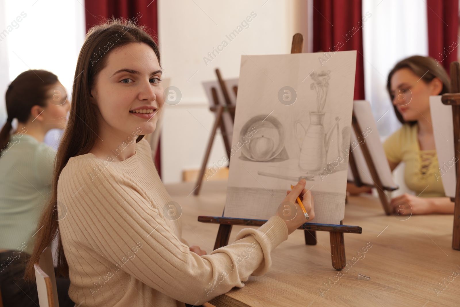 Photo of Group of women learning to draw at wooden table in class