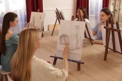 Photo of Group of women learning to draw at wooden table in class