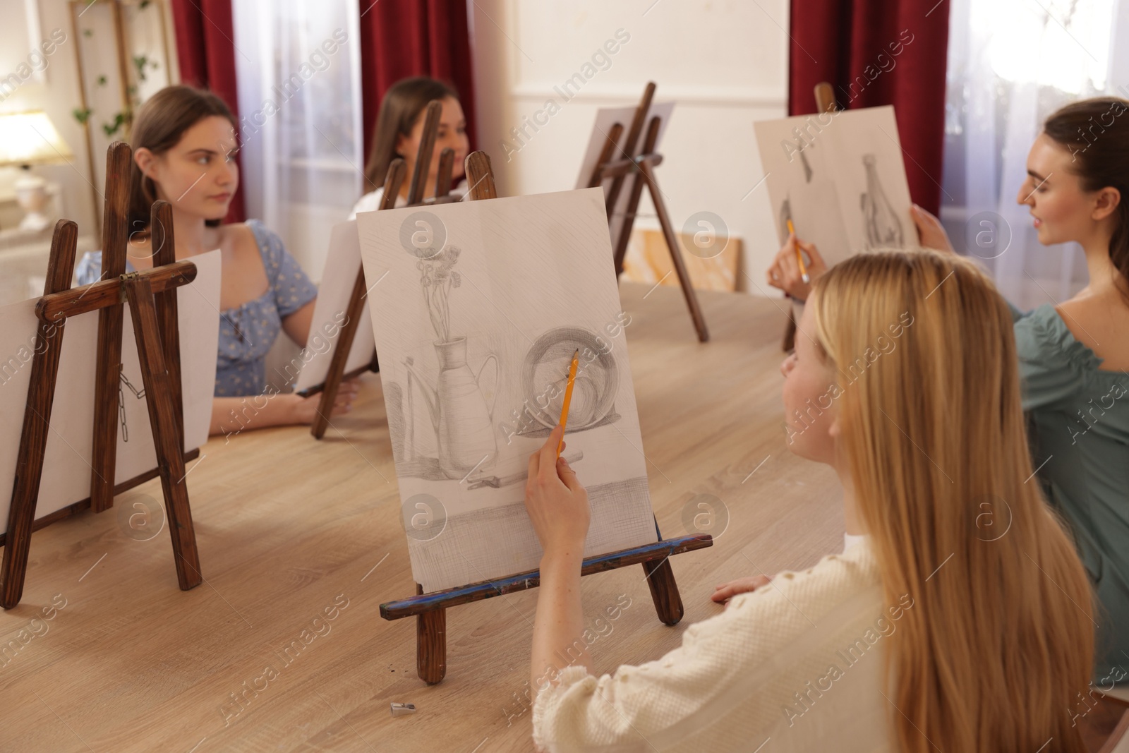 Photo of Group of women learning to draw at wooden table in class