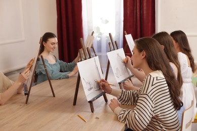 Photo of Group of women learning to draw at wooden table in class