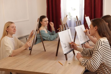 Photo of Group of women learning to draw at wooden table in class