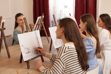 Group of women learning to draw at wooden table in class