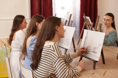 Photo of Group of women learning to draw at wooden table in class