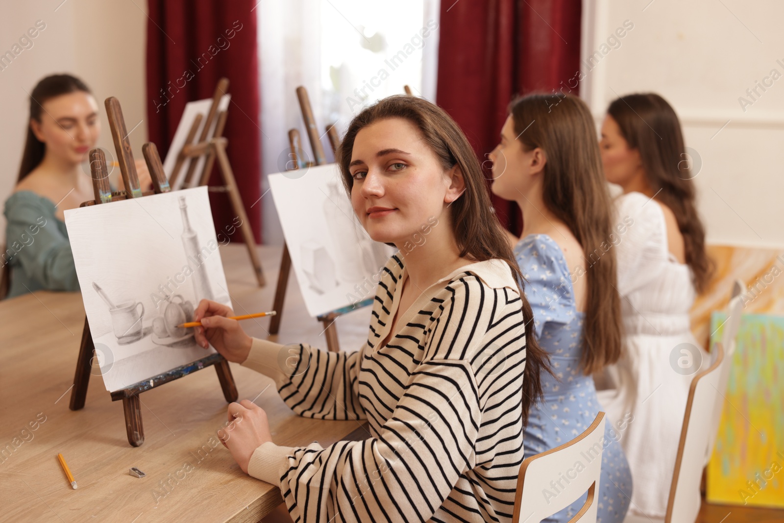 Photo of Group of women learning to draw at wooden table in class