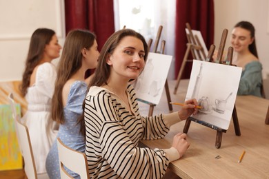 Group of women learning to draw at wooden table in class