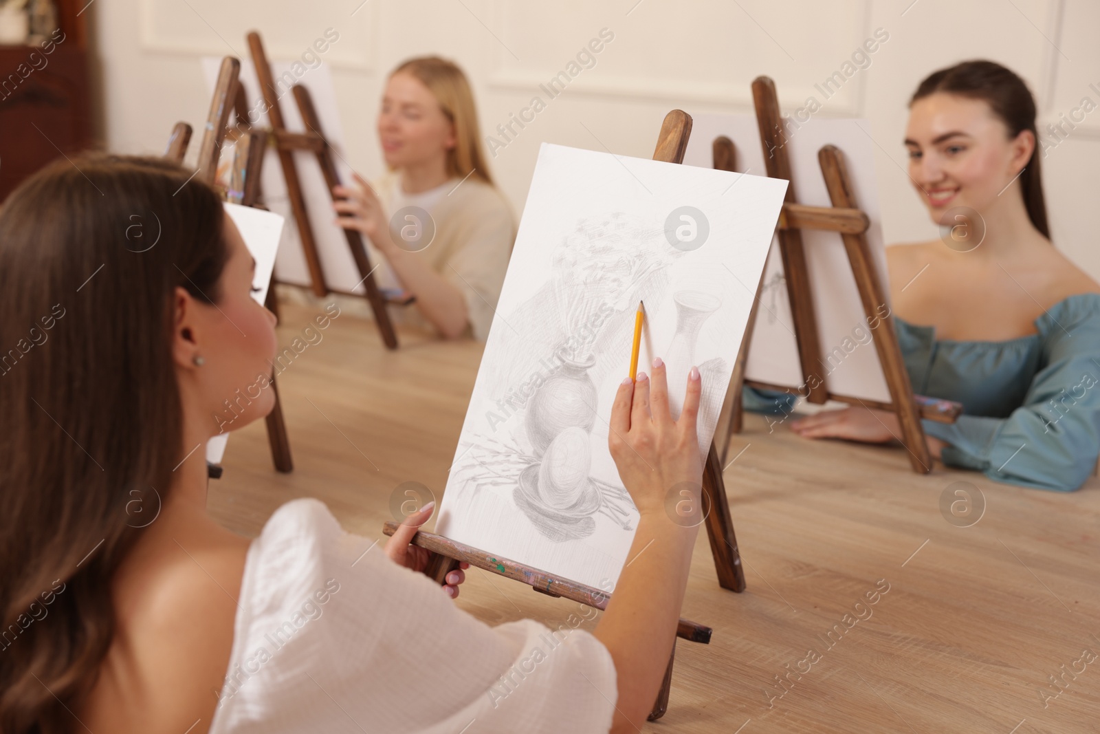 Photo of Group of women learning to draw at wooden table in class