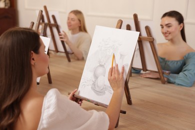 Photo of Group of women learning to draw at wooden table in class