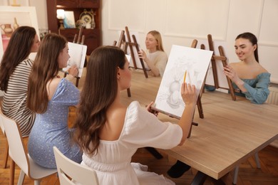 Photo of Group of women learning to draw at wooden table in class